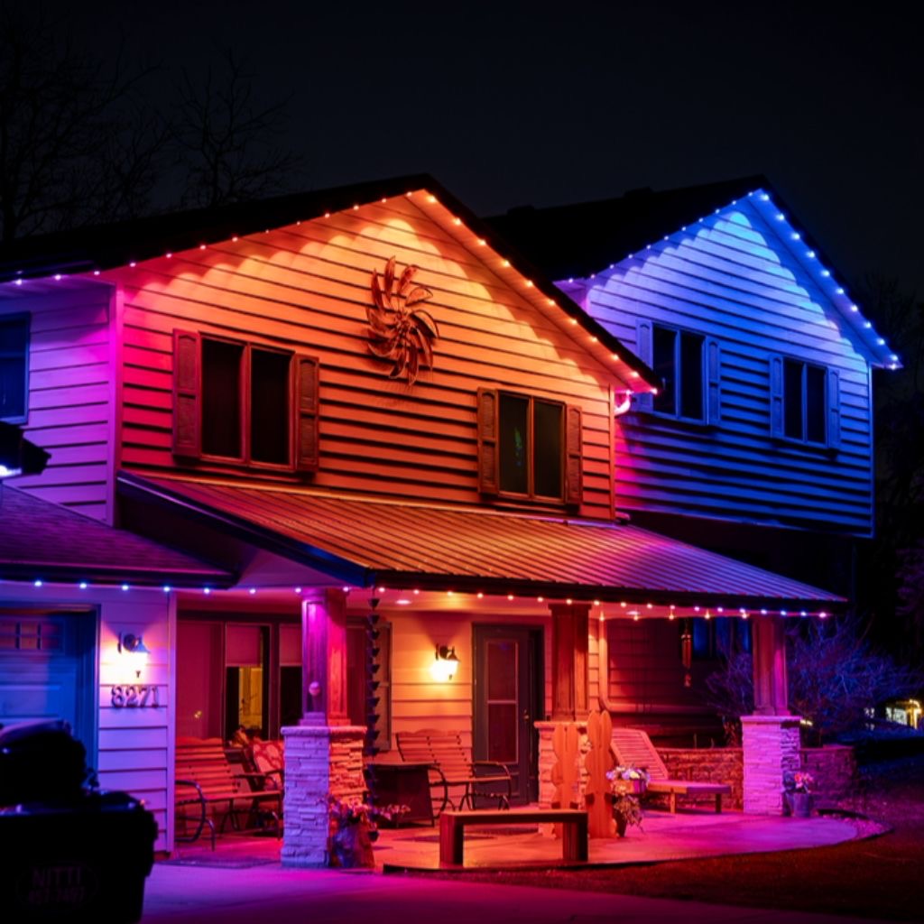 Two-story home illuminated with colorful permanent roofline lighting