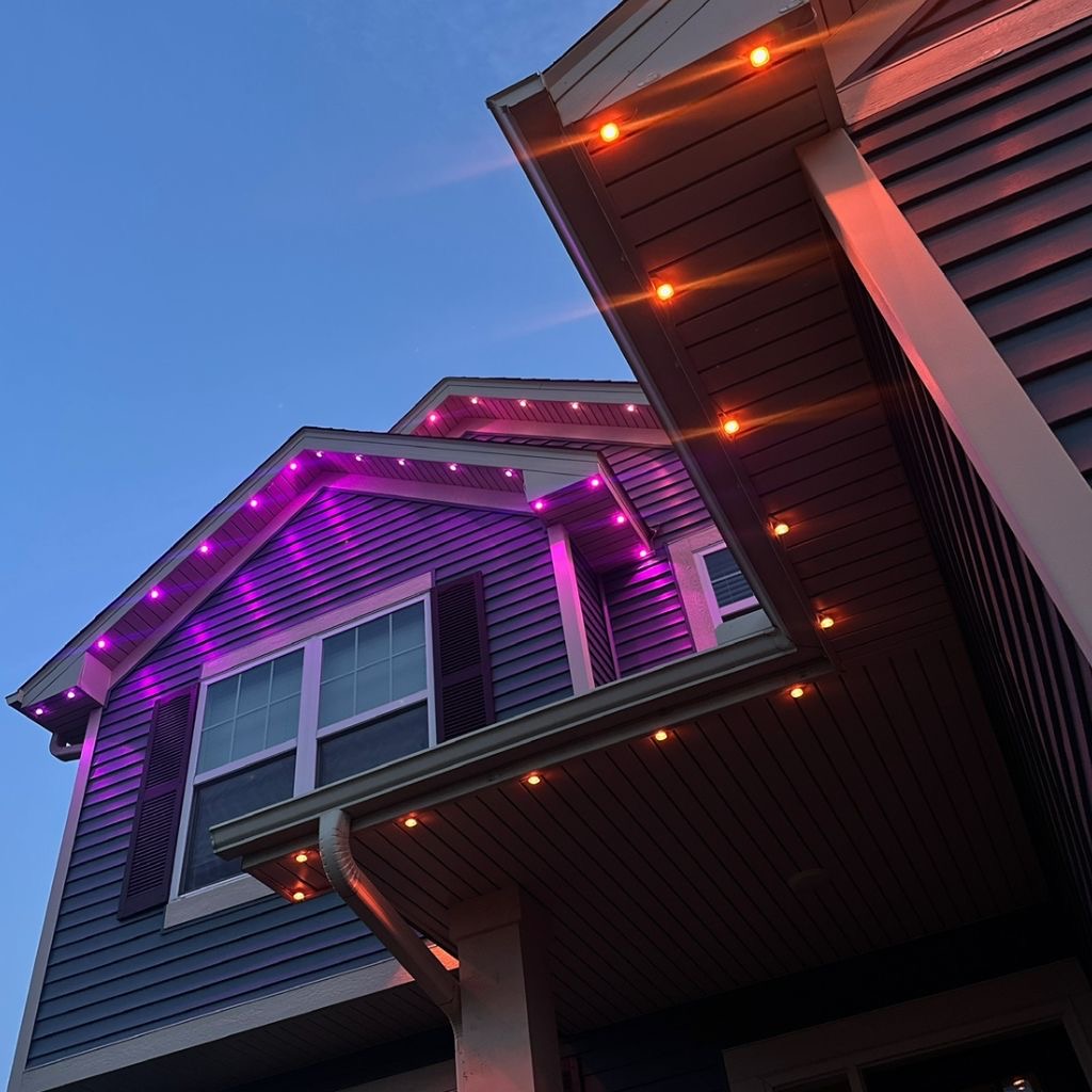 Close-up of permanent purple and warm white lighting installed under home eaves