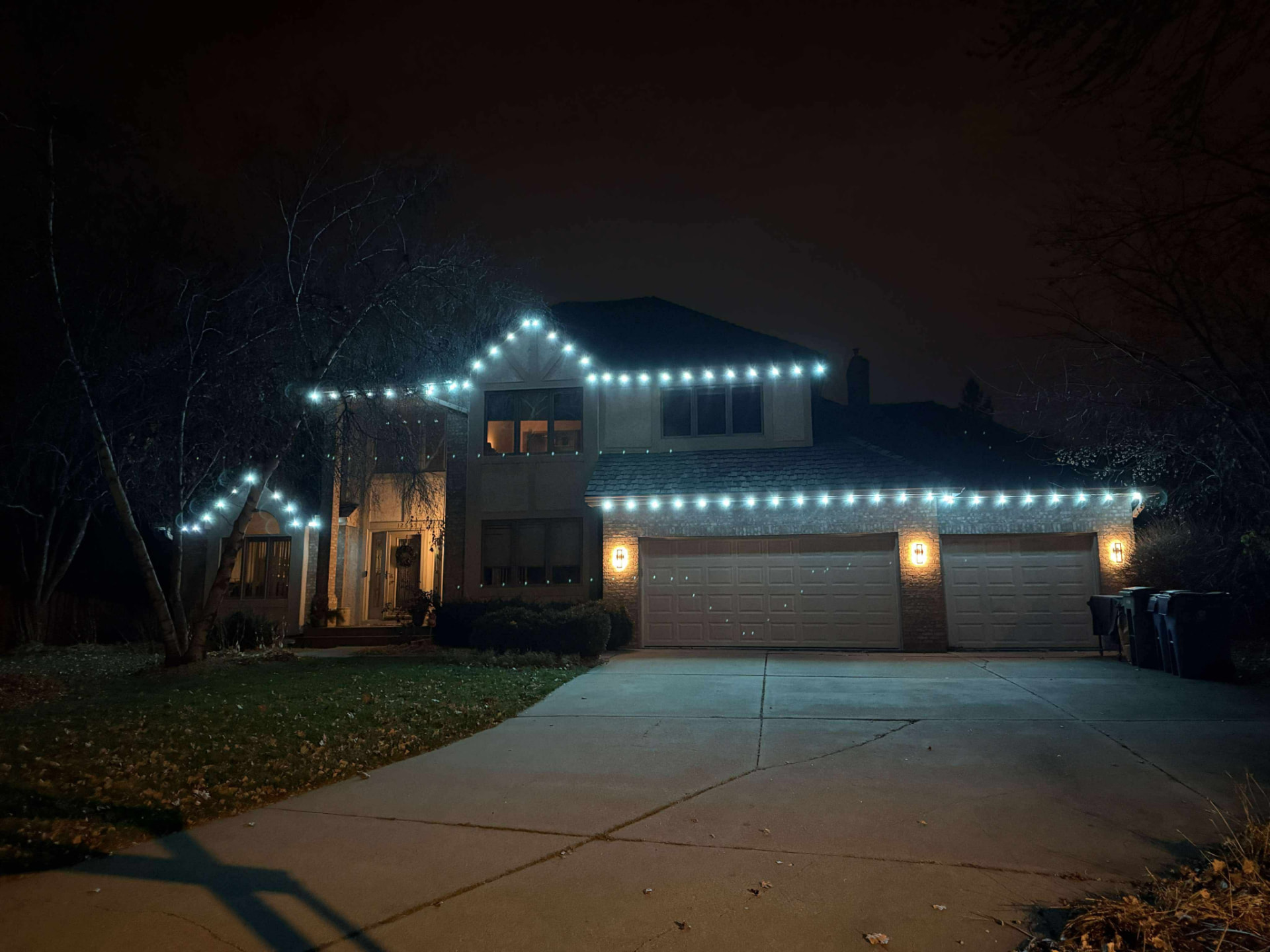 Large home with crisp white permanent roofline lighting at night