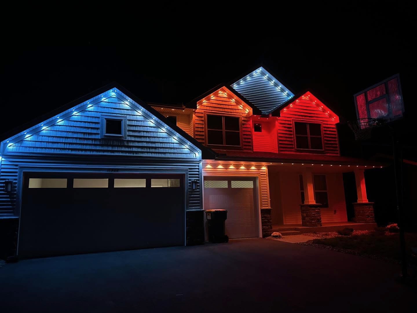 Two-story home illuminated with red, white, and blue permanent lighting